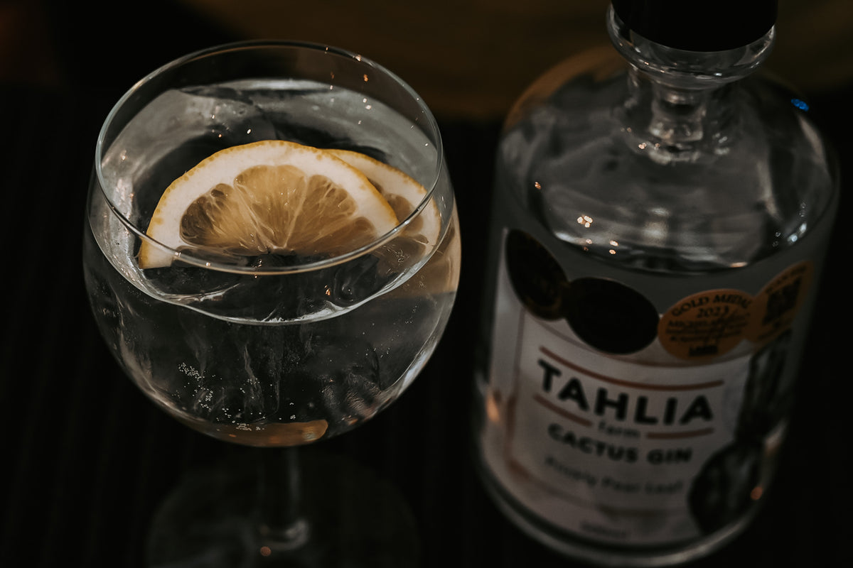 Gin and tonic with lemon beside a bottle of Tahlia Farm Cactus Gin